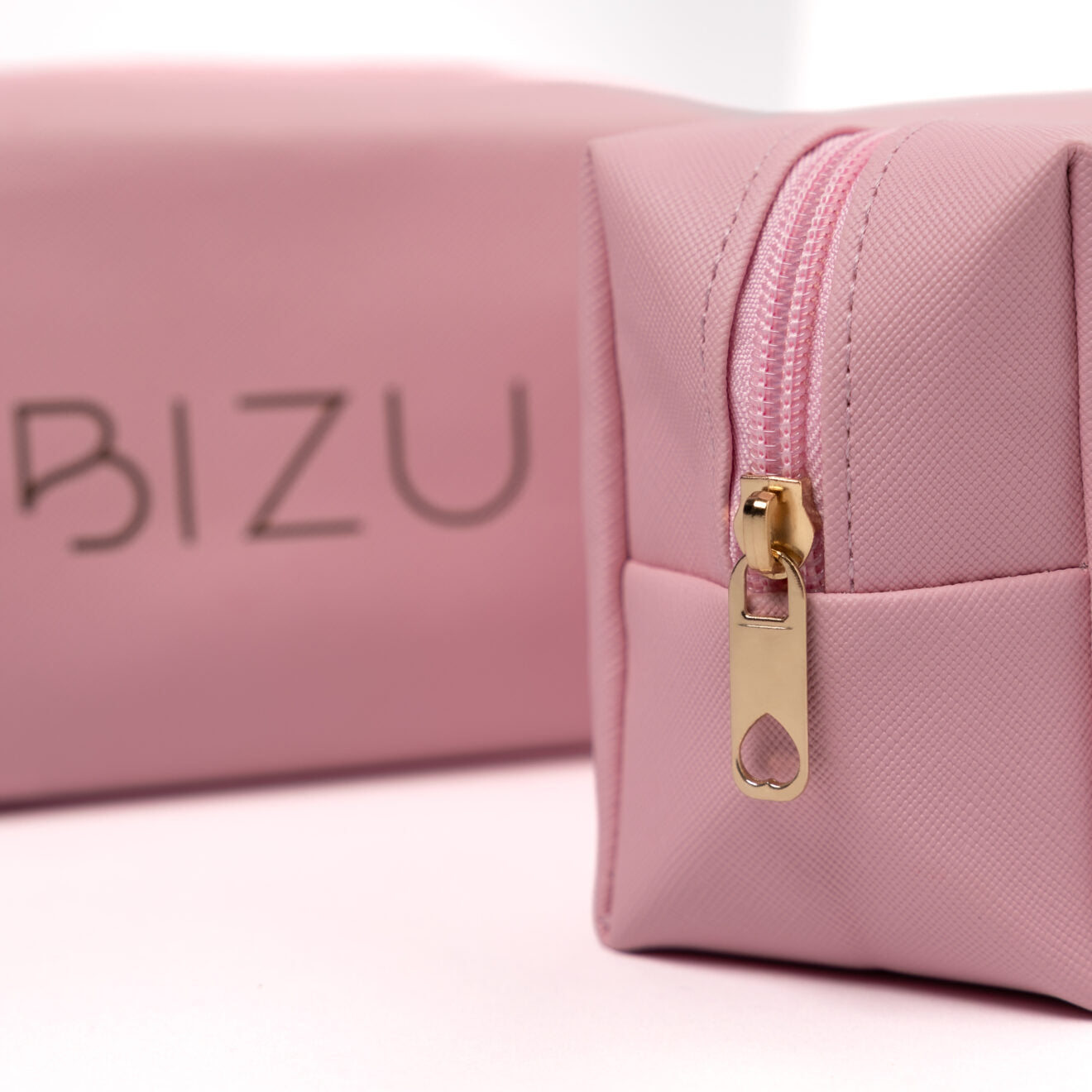 Pink cosmetic bag with gold zipper and 'BIZU' branding on a white background