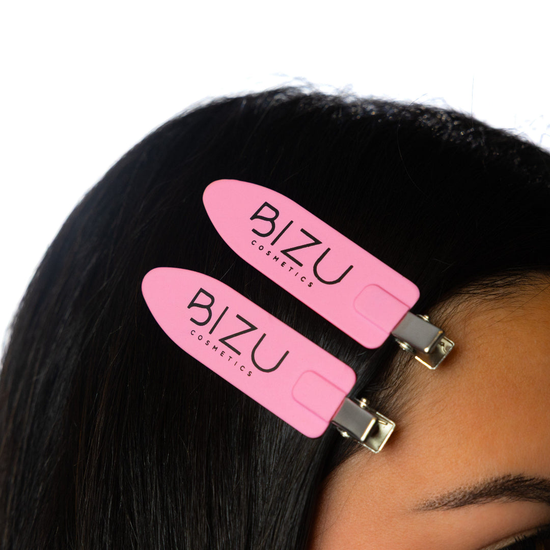 Pink hair clips with 'BIZU' branding on a person's hair against a white background