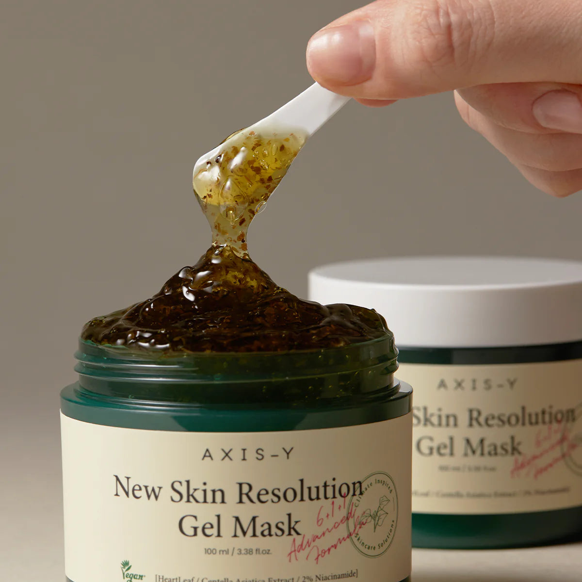 AXIS-Y New Skin Resolution Gel Mask with a hand applying the gel from a applicator.